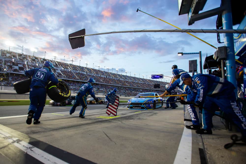The pit crew at a race helps to get a car ready at sunset.