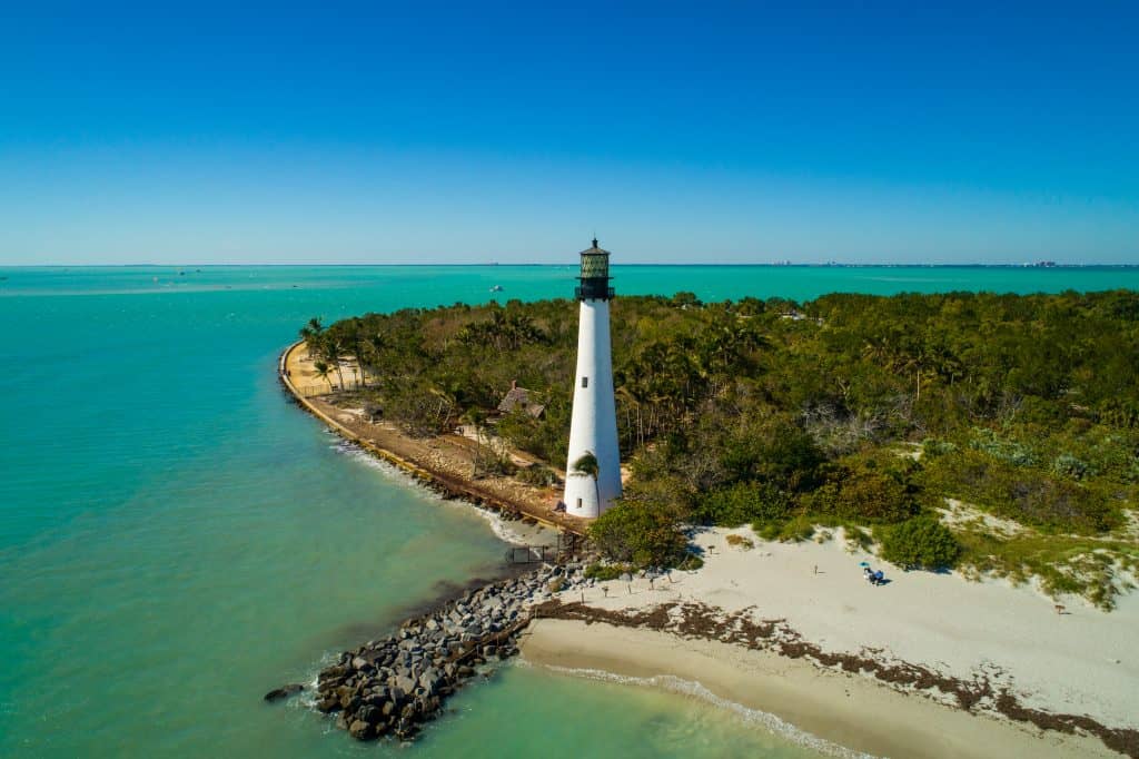 Aerial image of the lighthouse at Bill Baggs Cape Florida State Park overlooking the blue water.