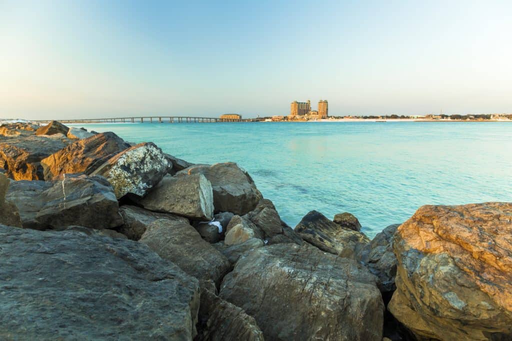 The rocky edge of Destin Harbor and its clear blue waters.