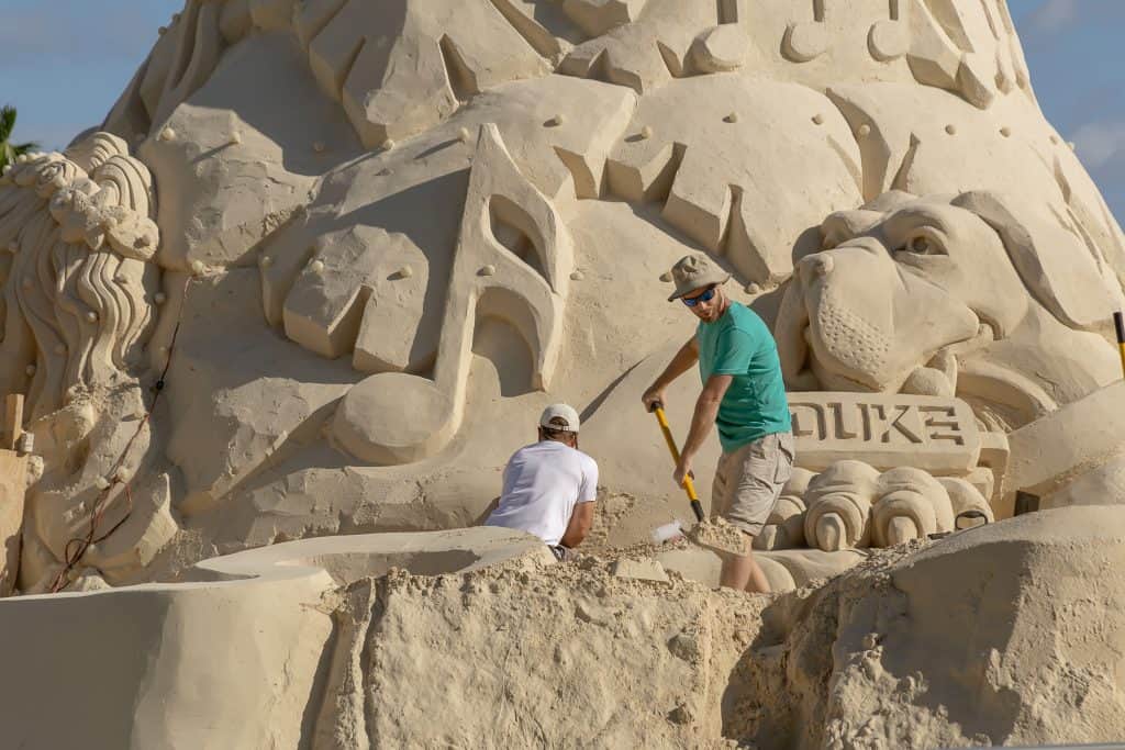 Two men working on building the giant sand tree at Sandi Land.