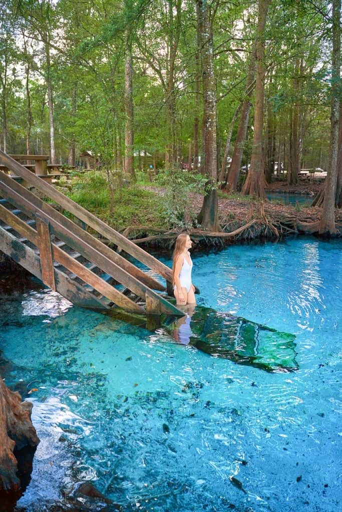 Woman walking down stairs into crystal clear blue water.