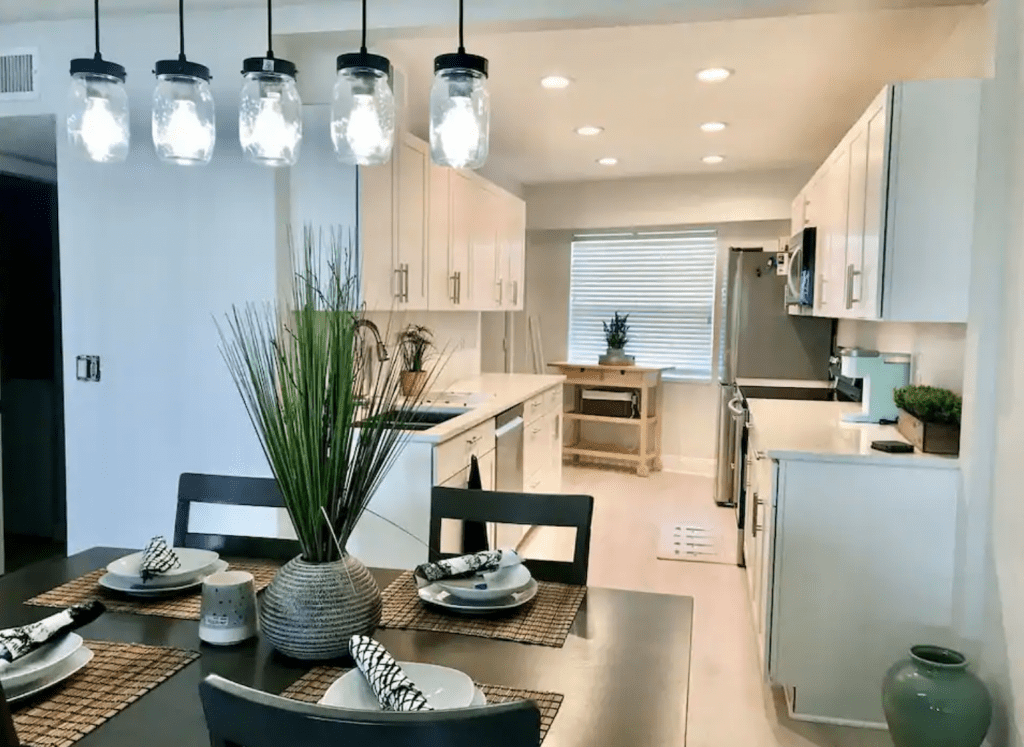 The posh, white kitchen and dining area of the the Beachside Condo, one of the best Clearwater Airbnbs.
