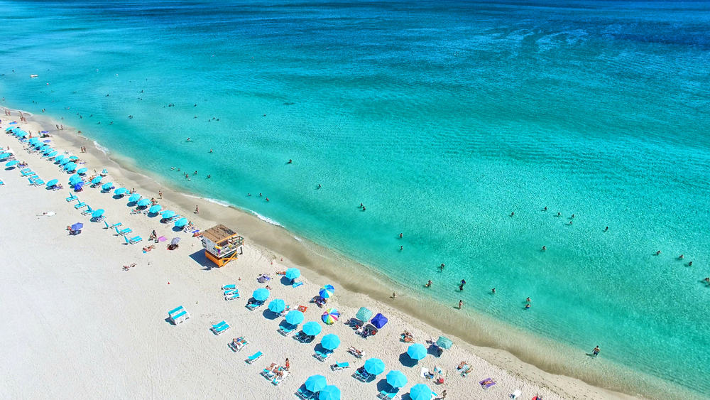 Miami Beach with bright blue water and blue parasols