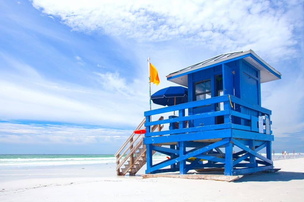 A brilliant blue lifeguard stand sits on the shores of Siesta Key Beach.