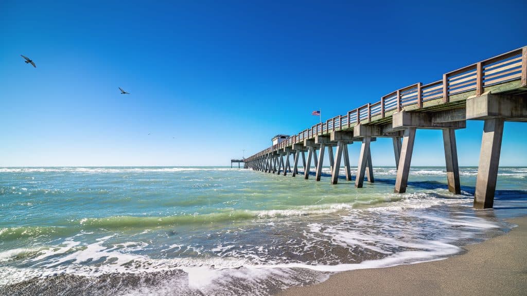 The emerald waters of the Gulf lap at the shorelines underneath the pier at Venice Beach, Florida.