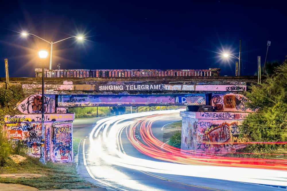 Night photo of Graffiti Bridge with light trails from cars driving underneath.