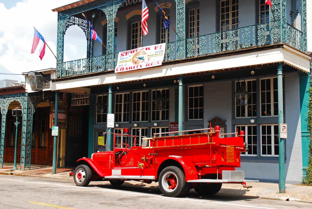 A red, vintage firetruck parked in front of a cool building in the Seville Quarter, one of the best things to do in Pensacola, FL.