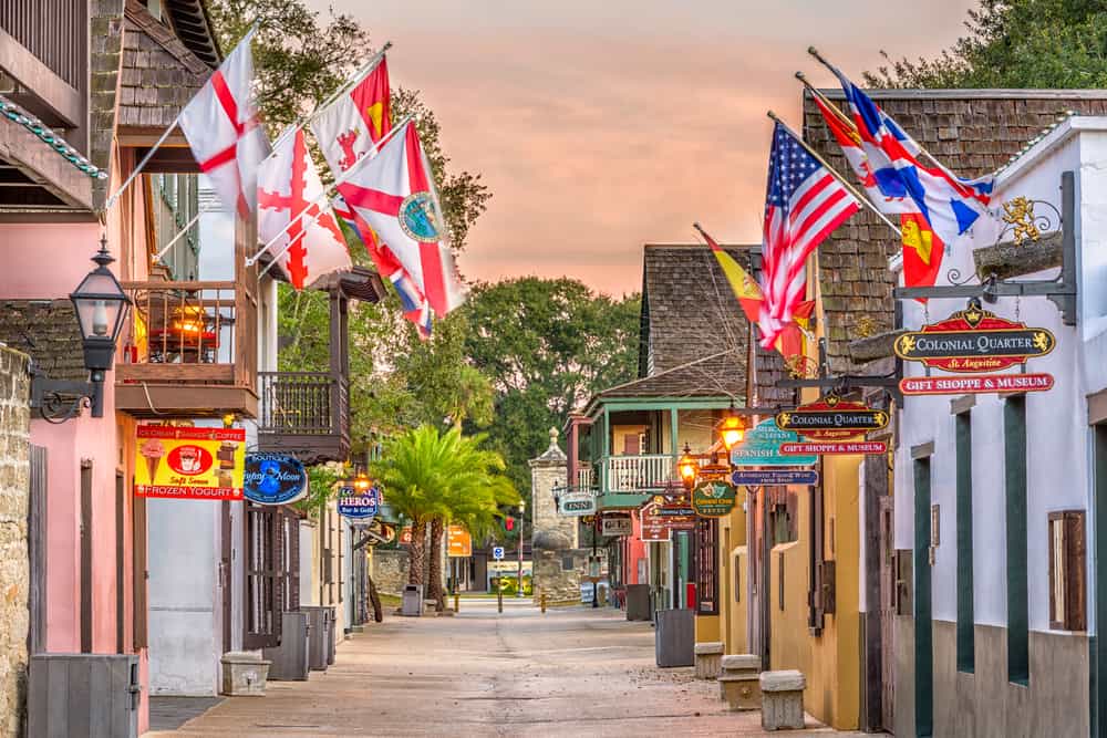 Downtown Saint Augustine at sunset with many different flags hanging over shopfronts.