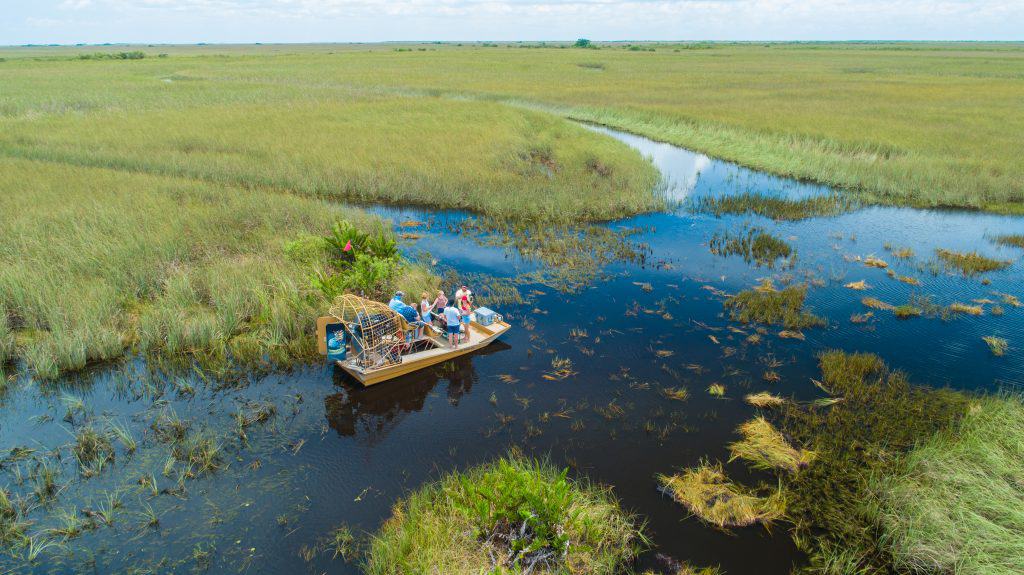 A pontoon floats on the murky waters of the Everglades, one of the best things to do in Marco Island.