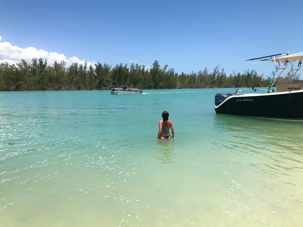 A swimmer wades from the boat to sink into the warm, blue waters of Keewaydin Island, one of the best Marco Island activities.