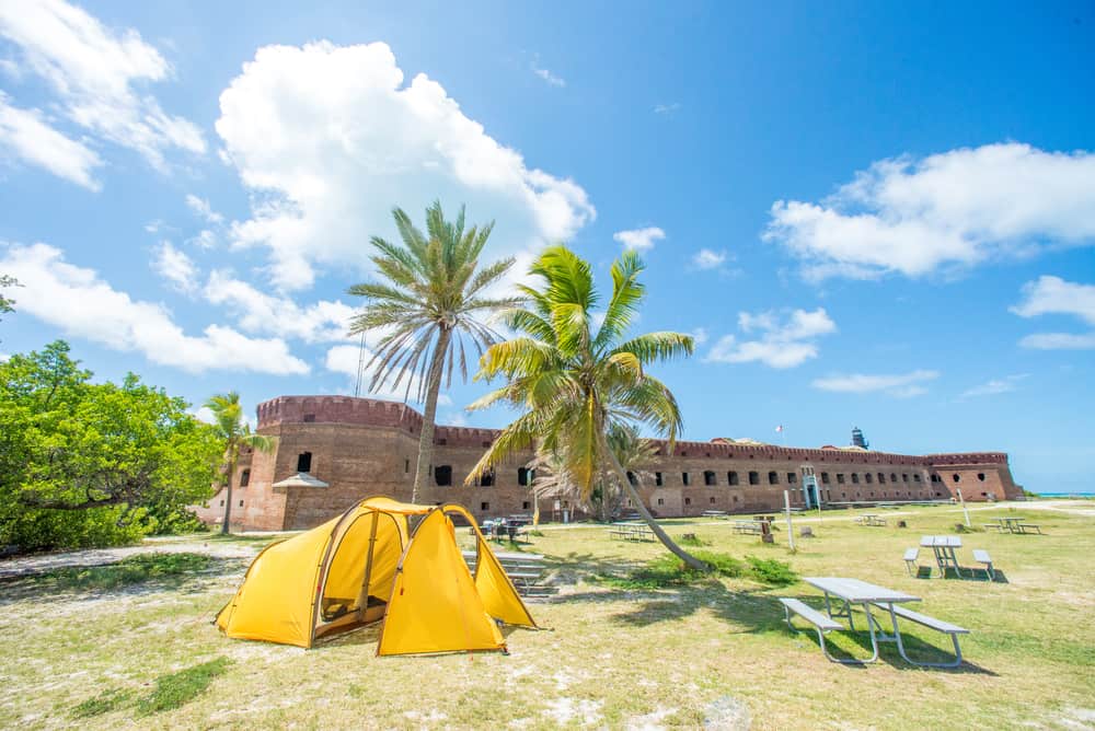 Yellow tent near picnic tables and palm trees outside of Fort Jefferson.