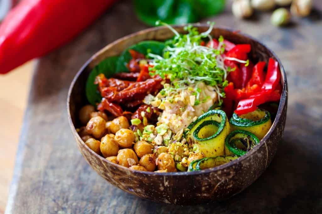 A vegan bowl, filled with vegetables, beans, and frisee.