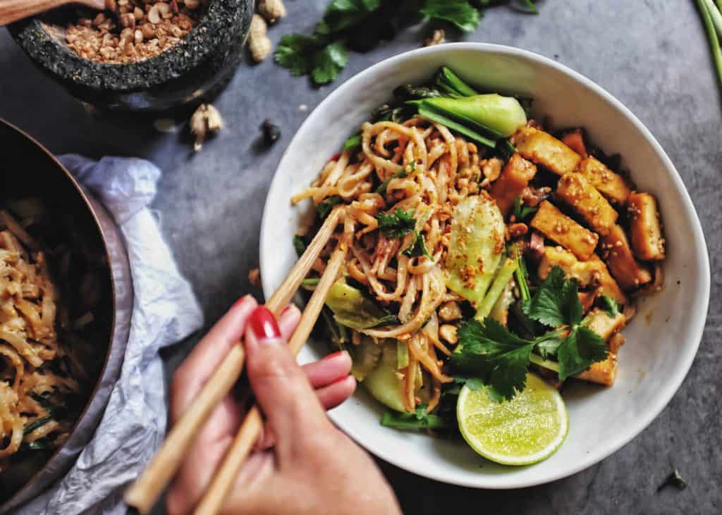 A bowl of noodles filled with vegetables and tofu.