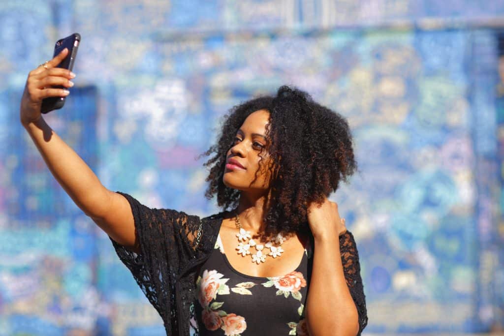 A woman poses for a selfie in front of the Wynwood Walls.