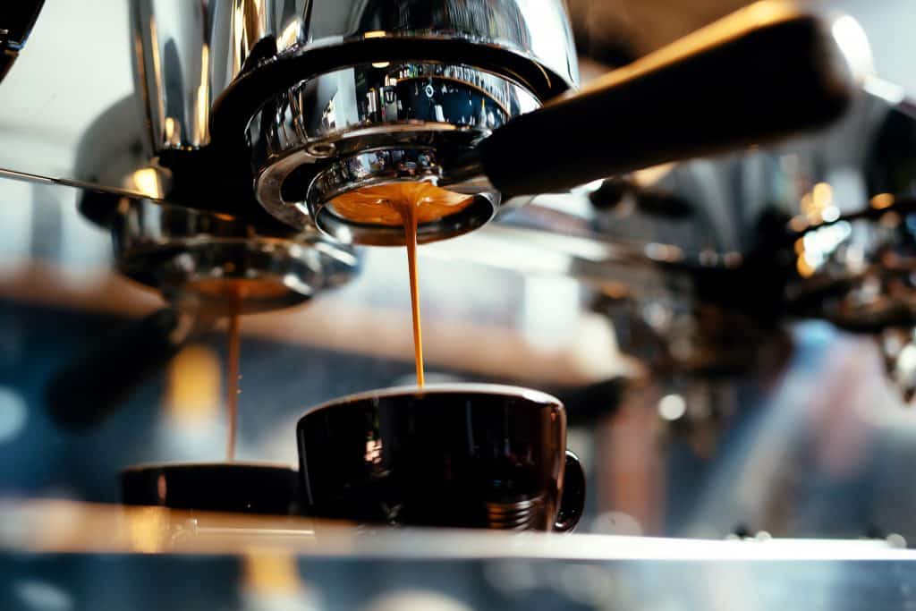 Espresso pours from the machine into the shot glass.