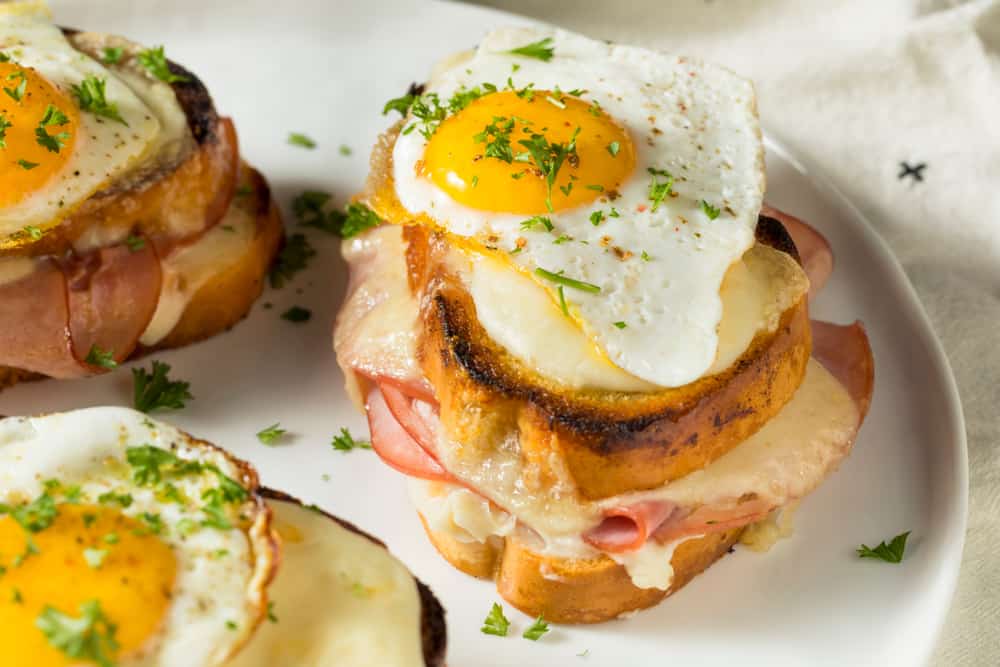 A plate with croque madame sandwiches with fried eggs on top.