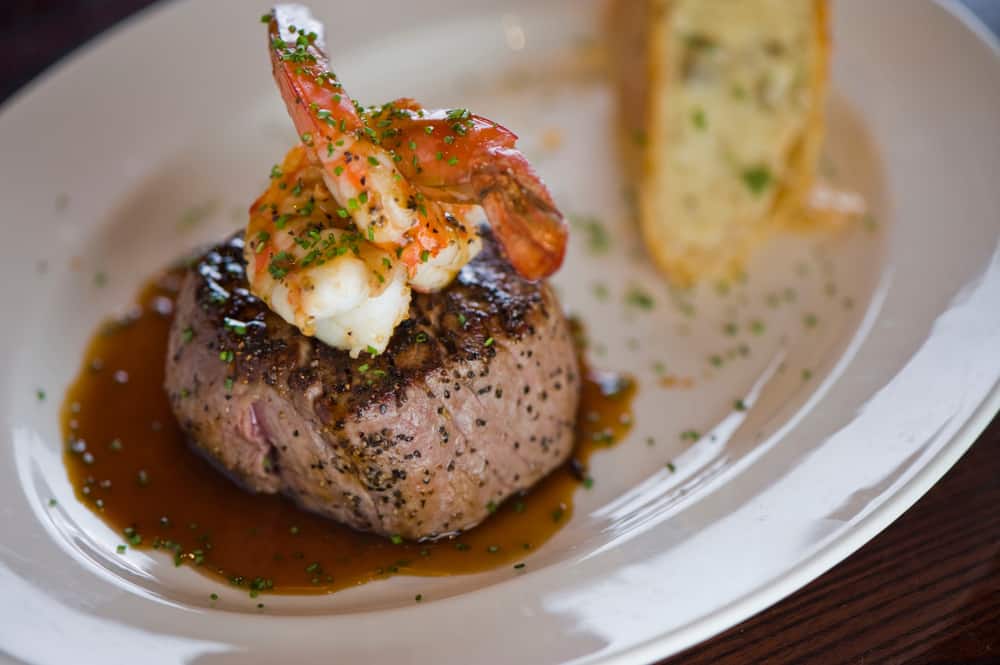 Plate of steak with shrimp on top.