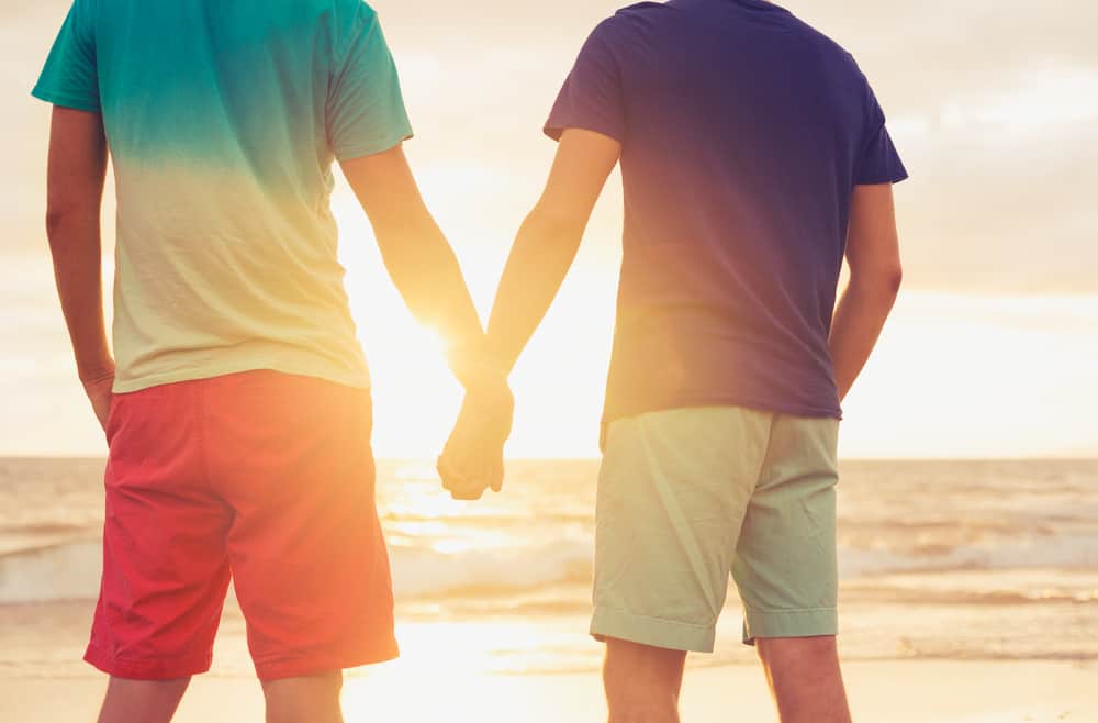 Gay Young Couple Walking Away Together Holding Hands Stock Photo