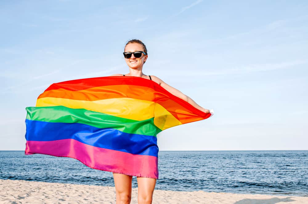 Girl holding a rainbow flag on a beach