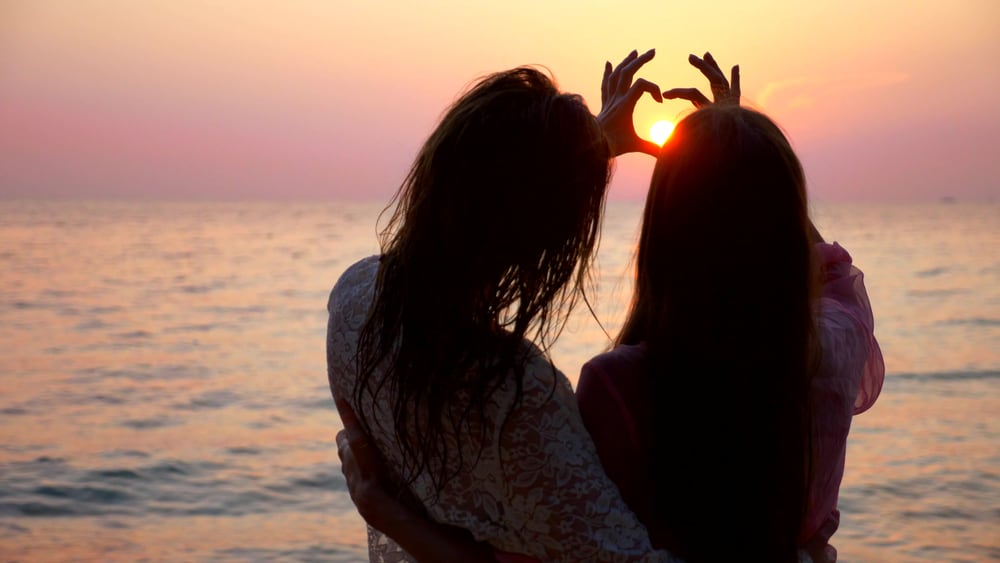 Two girls on a beach together in an article about gay beaches