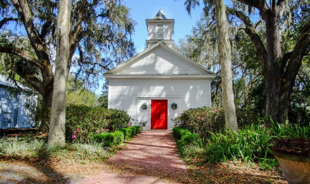 An old baptist church sits between oak and palm trees in Micanopy, one of the best small towns in Florida.