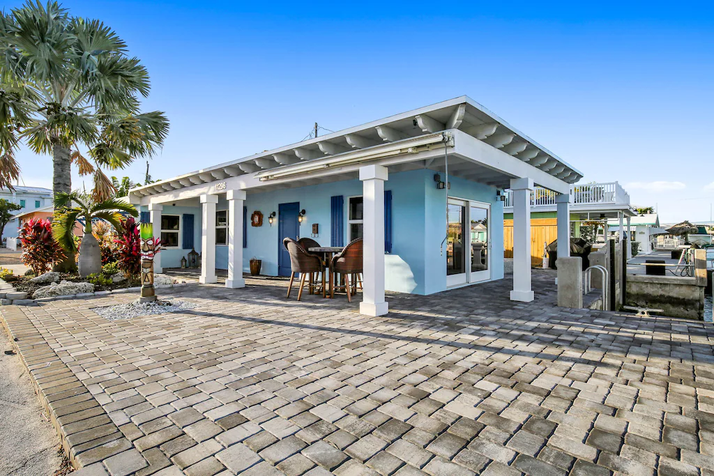 Photo of the exterior of a light blue canal front home which is a VRBO in Florida. 