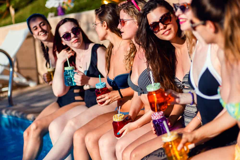 group of girlfriends at a poolside drinking cocktails