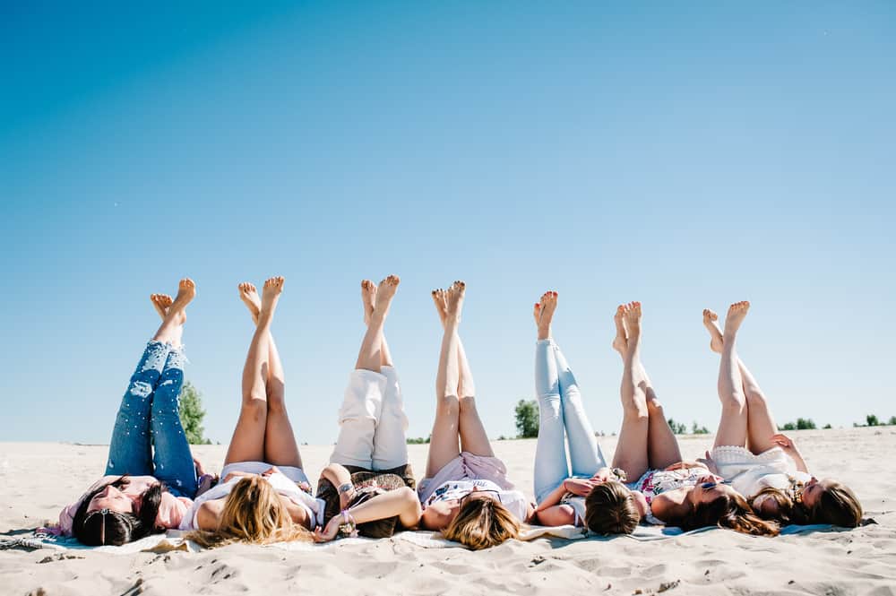 Seven girls on the beach with their legs crossed and in the air. Article is about Florida Bachelorette Party