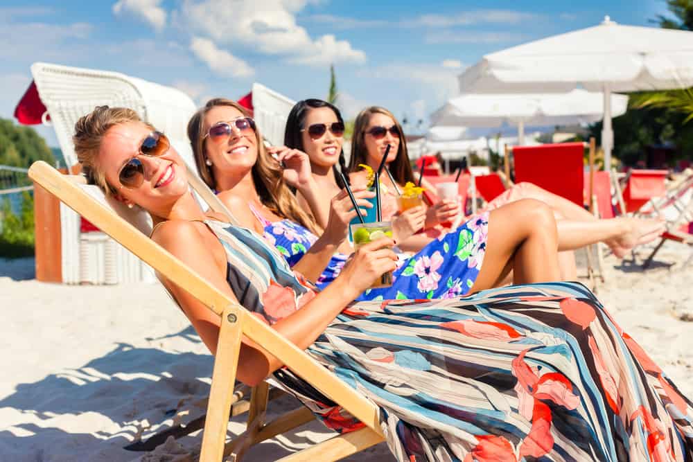 Four girls laid on the beach on sun loungers smiling at the camera in an article about Florida Bachelorette Party