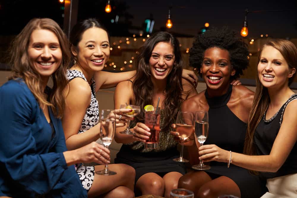 Five girls having a Florida Bachelorette Party at a bar with drinks smiling at camera