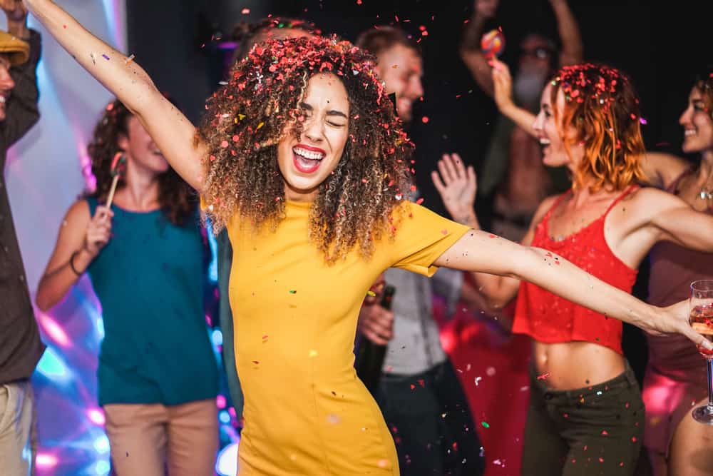 Friends dancing with girls in yellow dress dancing in the foreground with arms stretched out a Florida bacheloretteparty