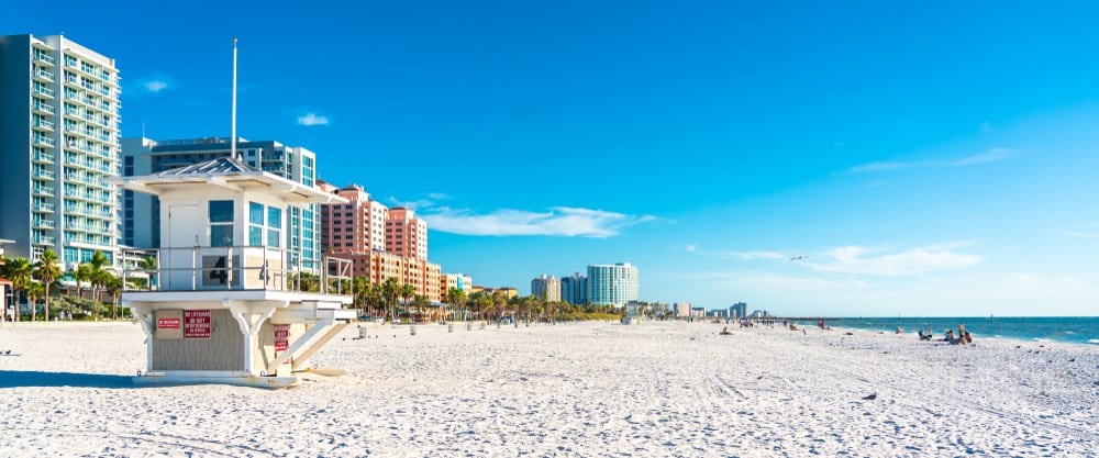 An empty, Clearwater shore aside a hotel strip with blue skies