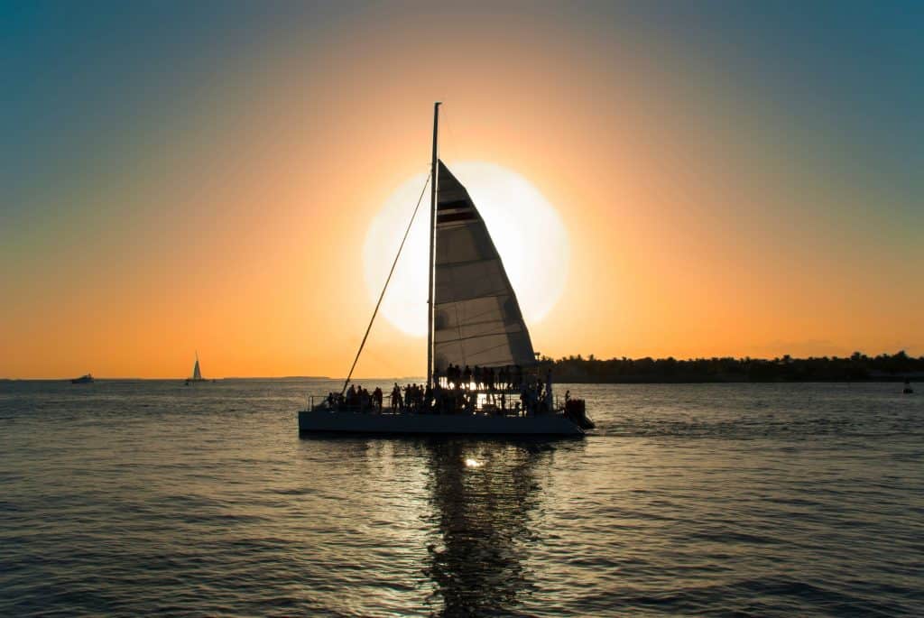 A catamaran sails on the bay at sunset during one of the best Naples boat trips.