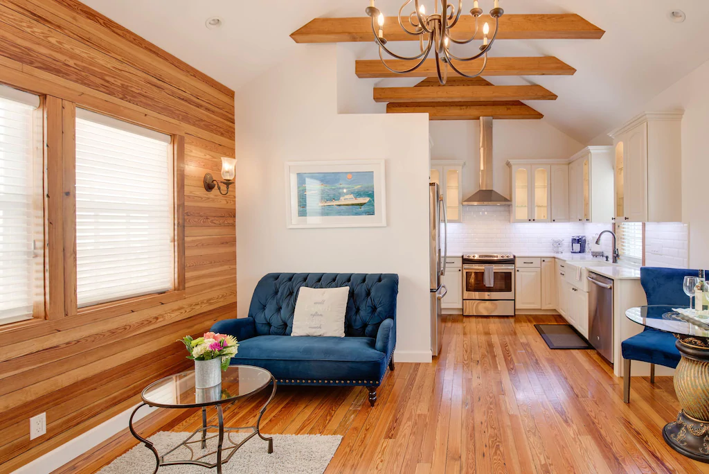Photo of a living room and kitchen inside a VRBO in Key West. It features wood floors and blue velvet lounge chairs. 