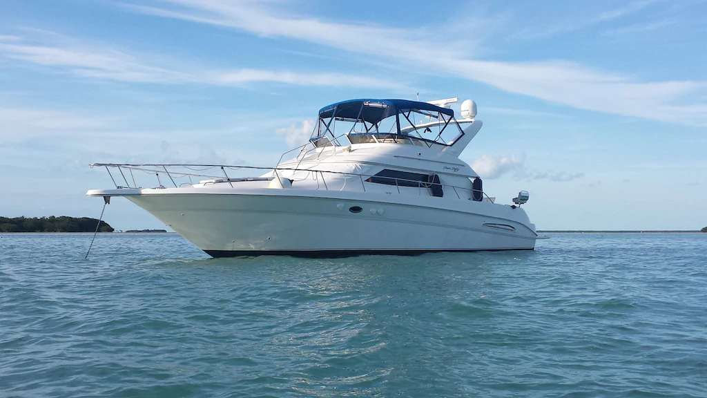 Photo of a 3/2 luxury yacht that is white with a blue canopy over the upstairs flybridge.