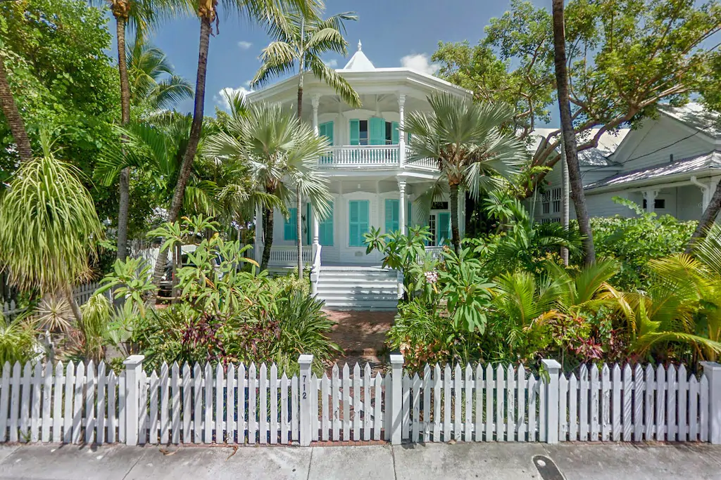 Photo of the front exterior of the "Octagon House" that is white with aqua shutters. 