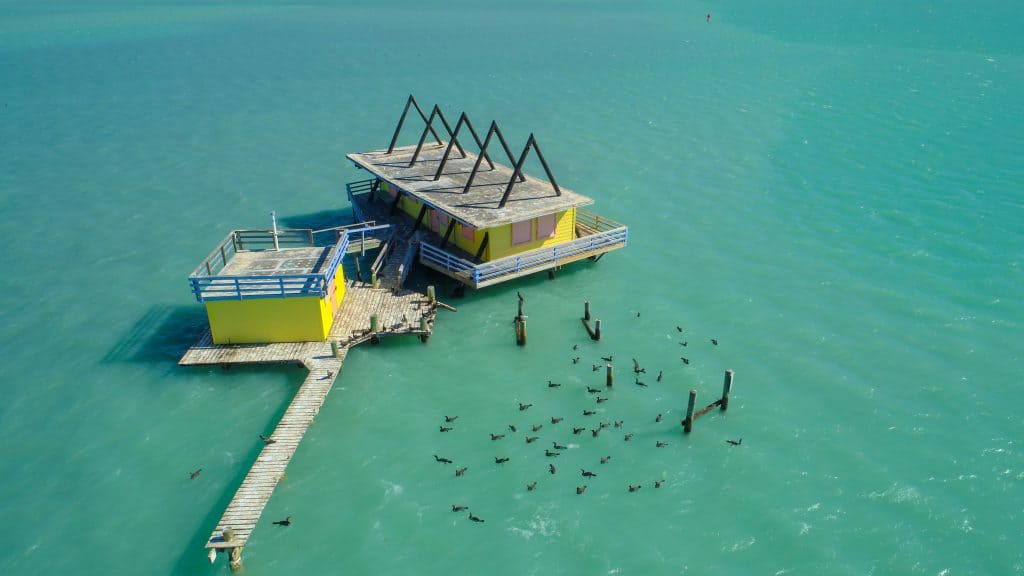 An abandoned colorful structure, a part of Stitsville, stands in the middle of the Atlantic Ocean.