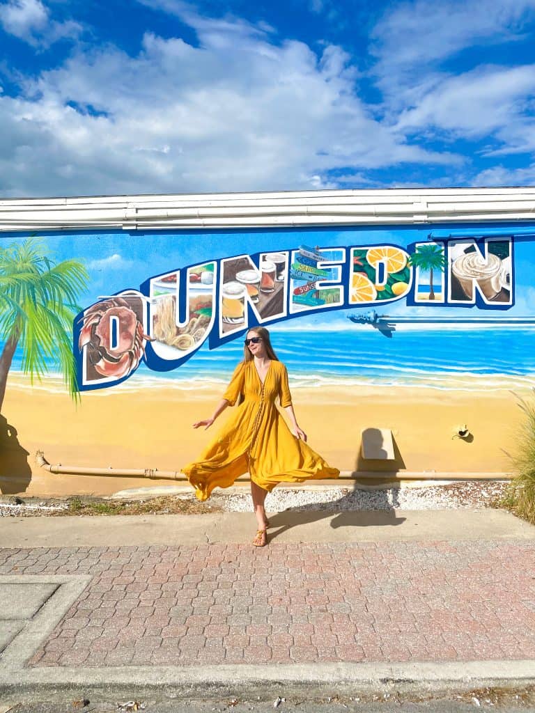 girl in yellow dress posing in front of a Dunedin wall mural