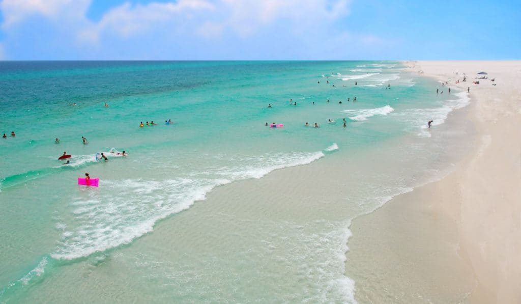 People swimming on emerald white shores