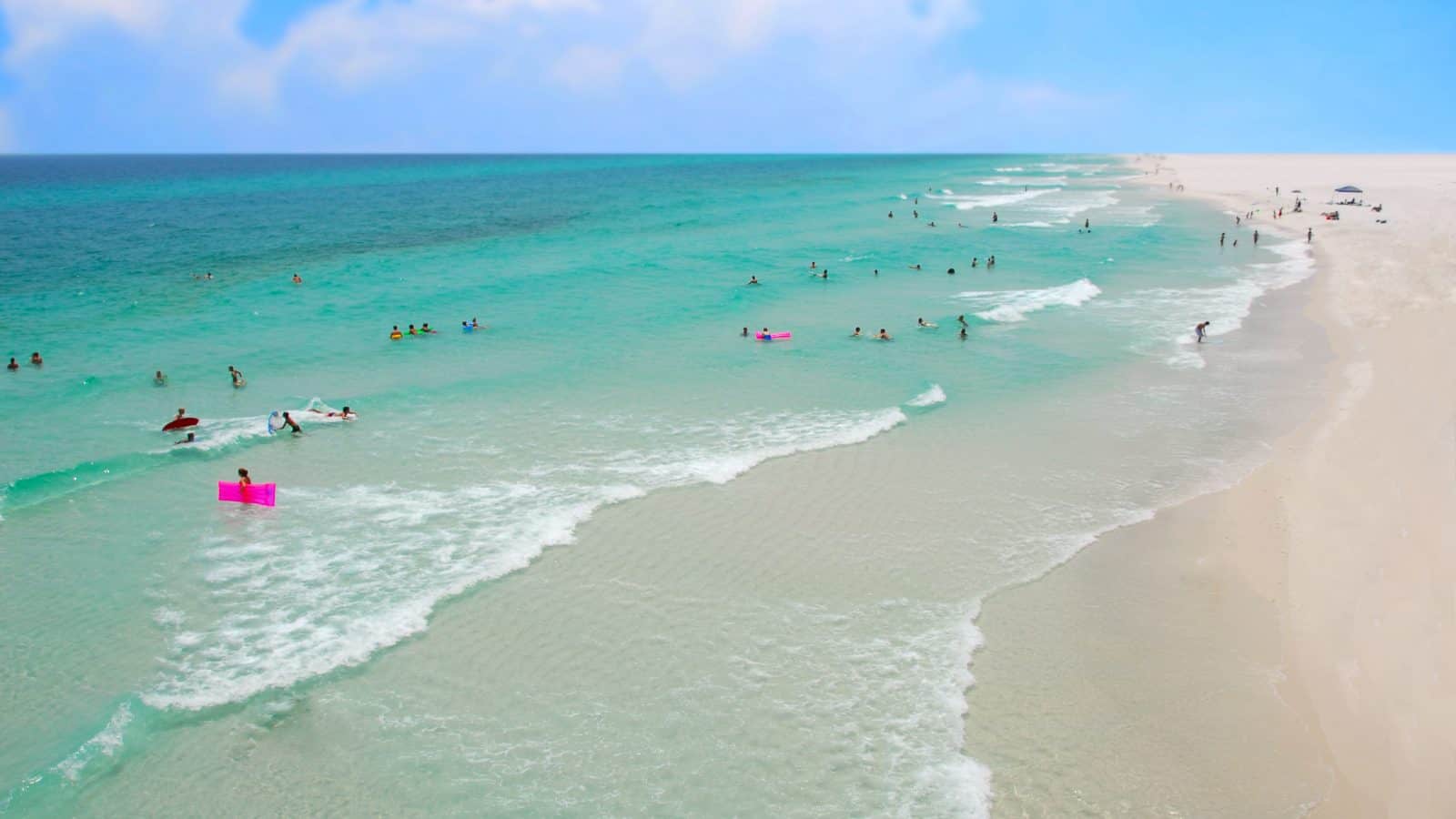 people swimming in the blue water on gulf islands national seashore with a blue sky