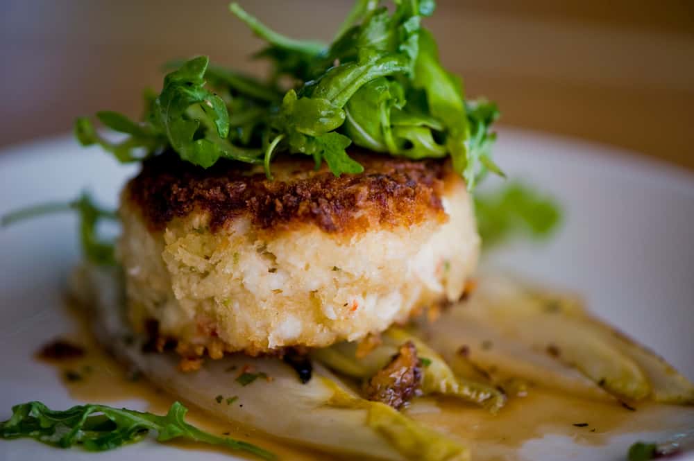 A jumbo lump crab cake over wilted endives topped with greens