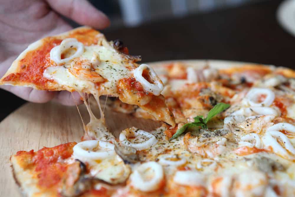 A seafood pizza with Alfredo sauce and calamari rings