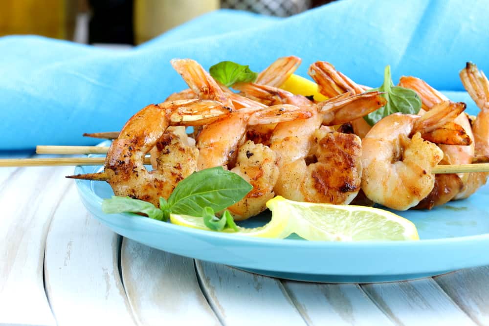 Jumbo shrimp skewers on a blue plate with a slice of lemon