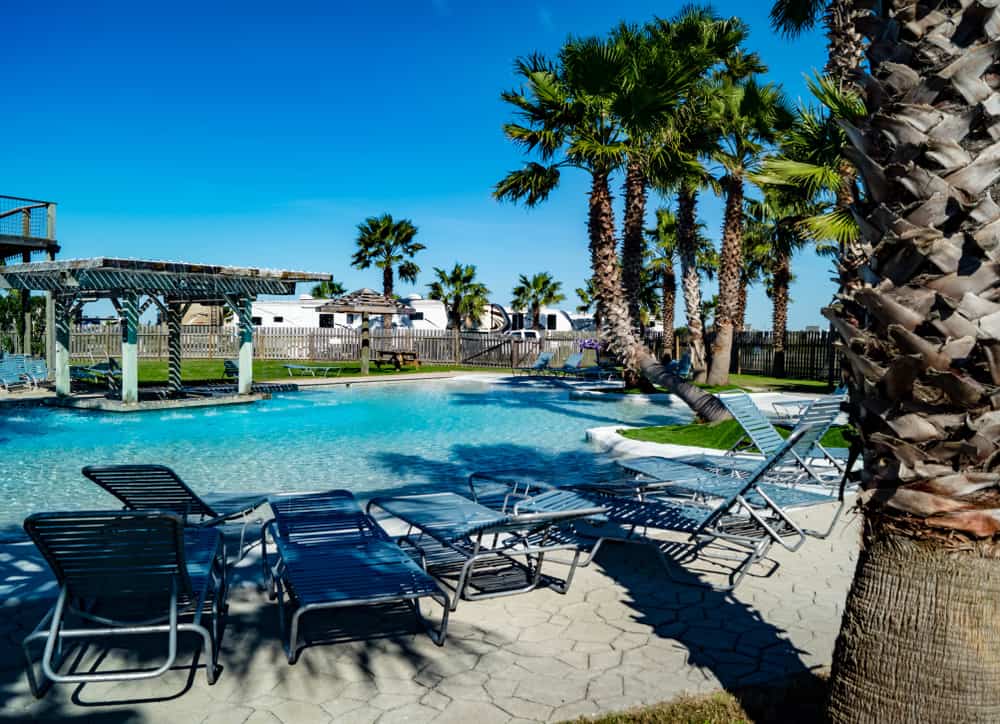 an RV resort with  pool, chairs, cabanas and motorhomes in the back