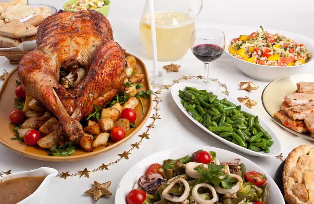 A Christmas meal on a table with turkey and many side dishes.