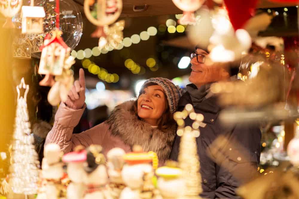 Two people at a Christmas market stall at night.