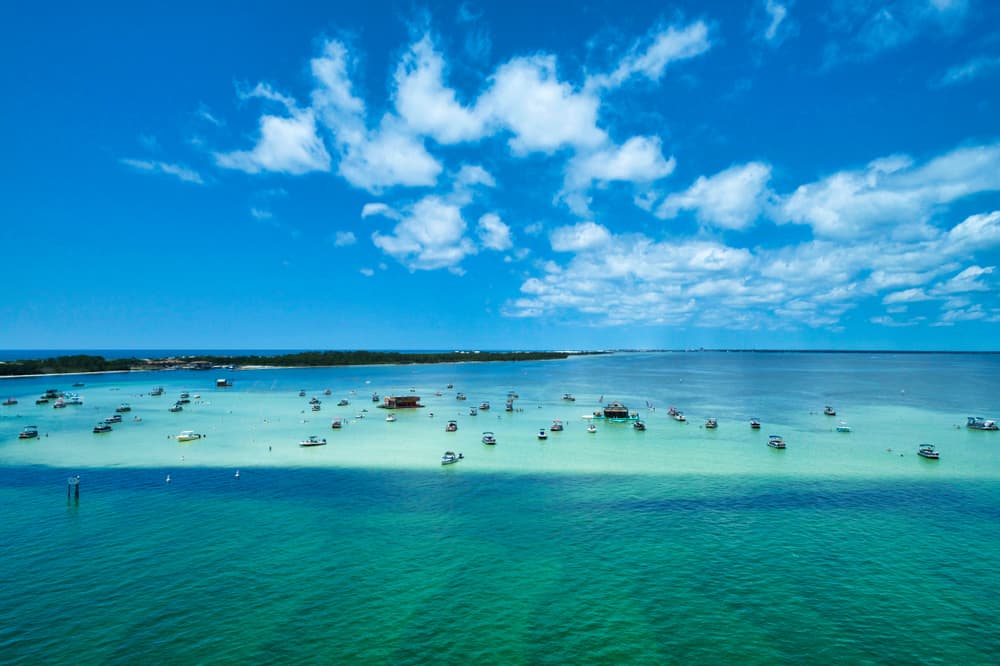 Boats gather over shallow blue green waters at beautiful crab island in  destin florida