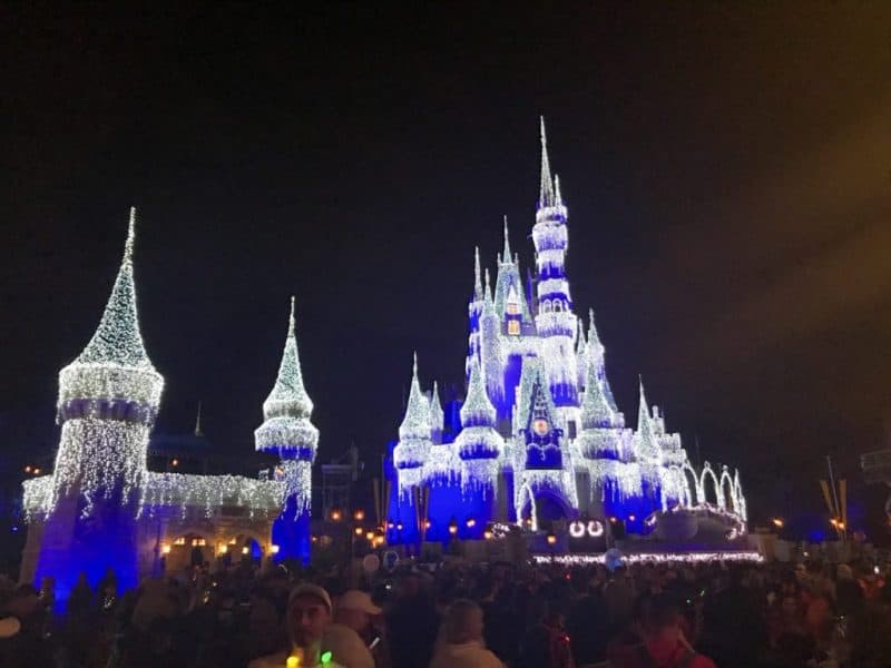 Cinderella's castle at the Magic Kingdom at night, all lit up with blue and white lights.