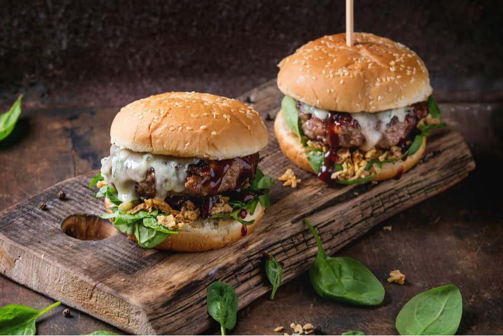 Burgers are piled high with melty cheese and a sesame bun
