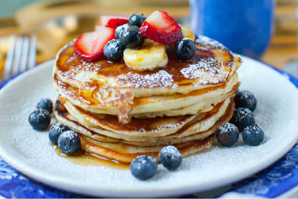 High stack of syrupy fresh fruit pancakes